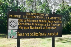 At the entrance of International Friendship Park, a sign highlights its recognition as a World Heritage Site and Biosphere Reserve. Nestled in lush greenery, it references the Cordillera de Talamanca-La Amistad and spans across Costa Rica and Panama's Parque Nacional La Amistad.