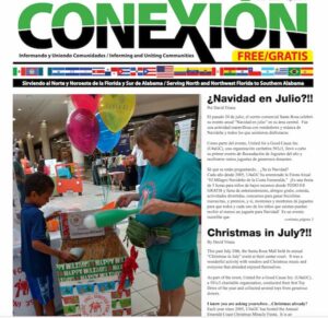 Una mujer con una camisa verde y un niño sostienen globos junto a una caja de donaciones en un centro comercial. El titular del periódico dice "CONEXION" con secciones en español e inglés que hablan sobre el evento de Navidad en julio de agosto de 2019. El artículo incluye fotos del evento y la asistencia del gobernador.