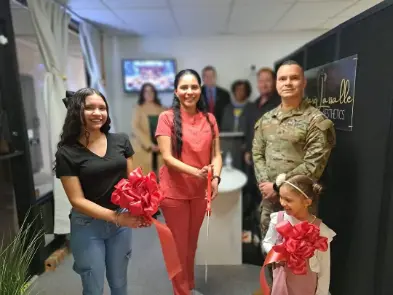 a group of people standing in a room with a woman holding a red ribbon