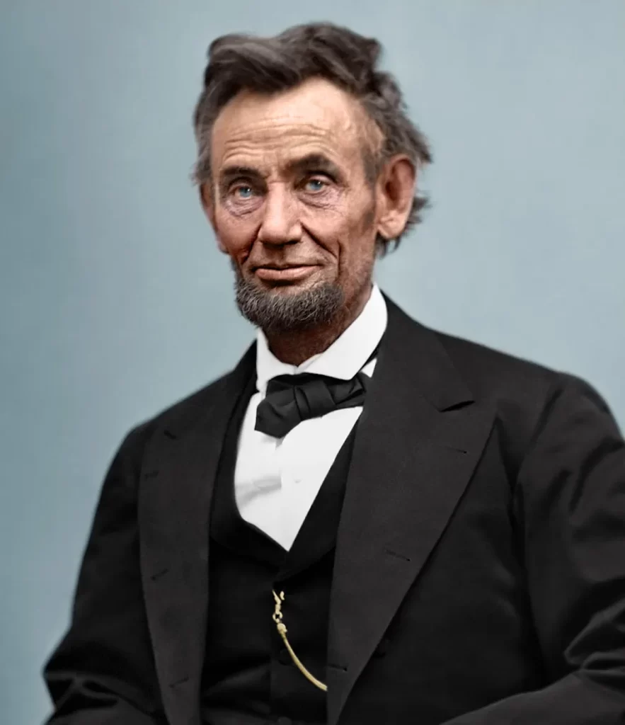 A colorized portrait of a bearded man, reminiscent of Abraham Lincoln, in a black suit with a bow tie against a neutral background. He has a serious expression and is seated, with a chain visible on his vest.