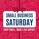 A red background with white floral patterns features a central white box with bold blue text reading "Small Business Saturday." Below in smaller text: "Shop Small. Make a Big Impact." A red bow decorates the top of the box.