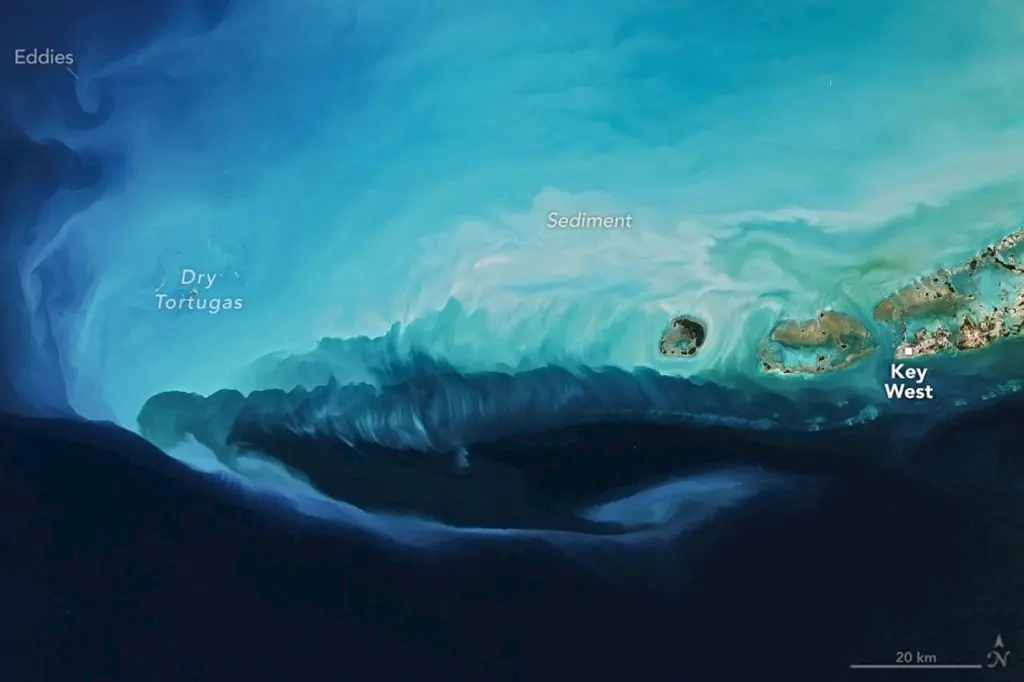 Satellite image of the Florida Keys and surrounding ocean, showing turquoise and deep blue waters, with Key West labeled on the right and Dry Tortugas on the left; lighter areas indicate sediment.