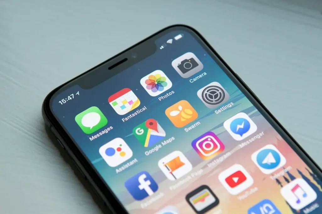A close-up of a smartphone screen displaying various app icons, including Messages, Photos, Camera, Google Maps, Settings, Facebook, Instagram, and Messenger. The time shown is 15:47.