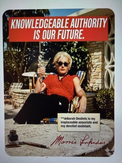 A person in sunglasses and a red blouse sits outdoors with a drink, under a sign reading “KNOWLEDGEABLE AUTHORITY IS OUR FUTURE.” Text below praises Deborah Desilets as an irreplaceable associate and devoted assistant, recognizing her vital role in shaping our Human Legacy amidst the evolving interplay of AI and truth.