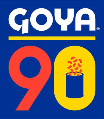 Goya logo above a large red "9" and yellow "0" on a blue background; inside the "0" is a can with red beans spilling out, celebrating 90 years of GOYA FOODS' commitment to communities, including food donation efforts after earthquakes in Venezuela.